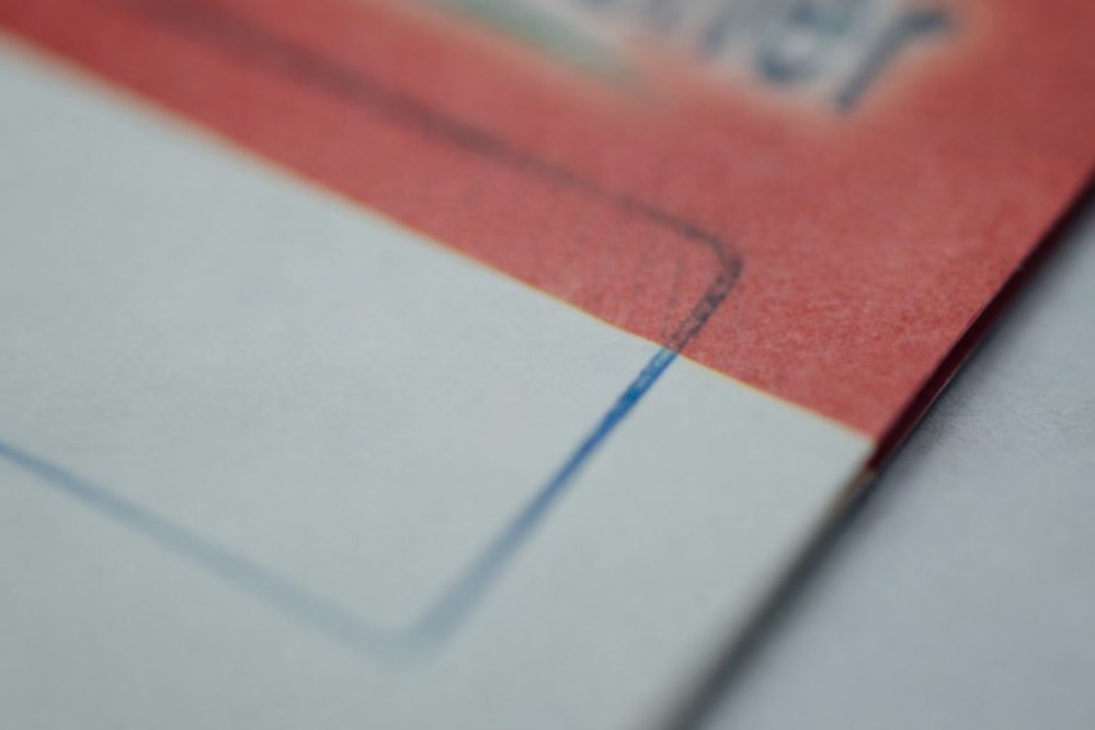 Lähikuva paperista, jossa sininen viiva ja osittain punainen alue.
