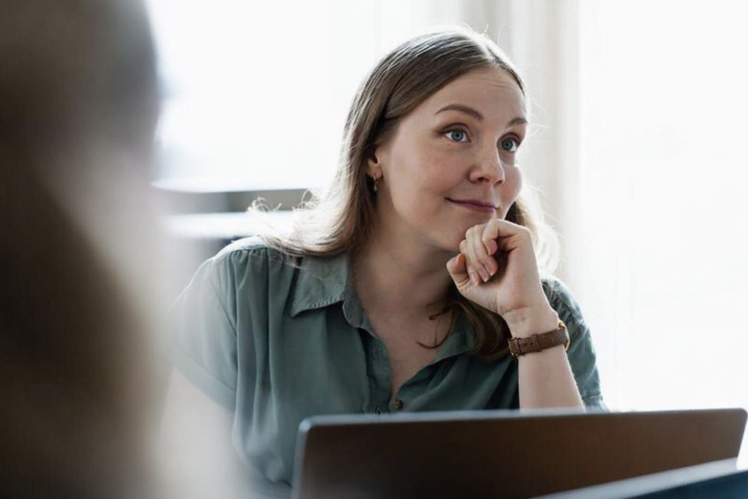 Nainen kuuntelee tarkkaavaisesti, ilme pohtiva kansainvälisen perinnän kokouksessa.